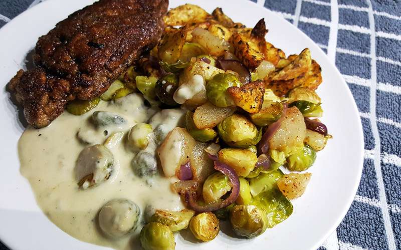 Zelfgemaakte kipschnitzel met gorgonzolasaus en aardappelen en spruitjes uit de oven